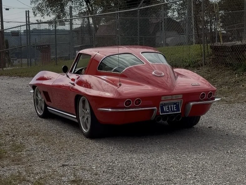 Finished red C2 split-window coupe rear view on a gravel driveway.