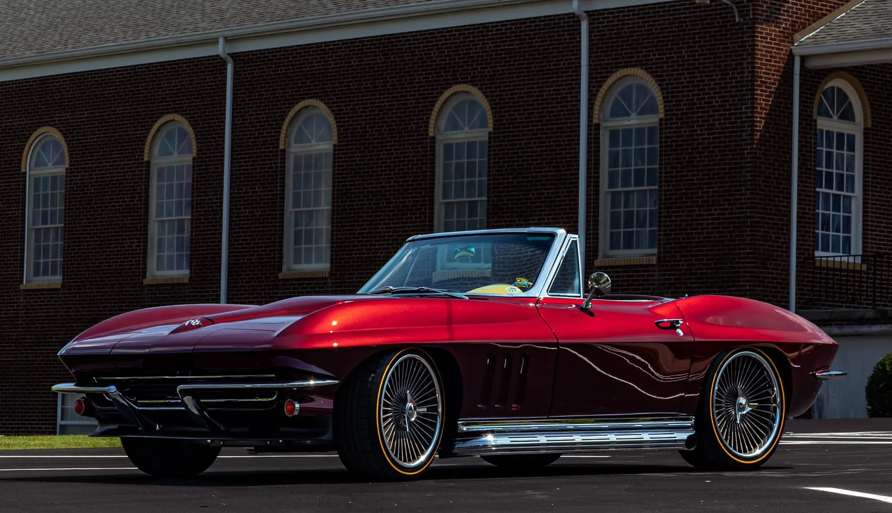 Ruby red C2 Corvette convertible front three-quarter view with side exhaust pipes.