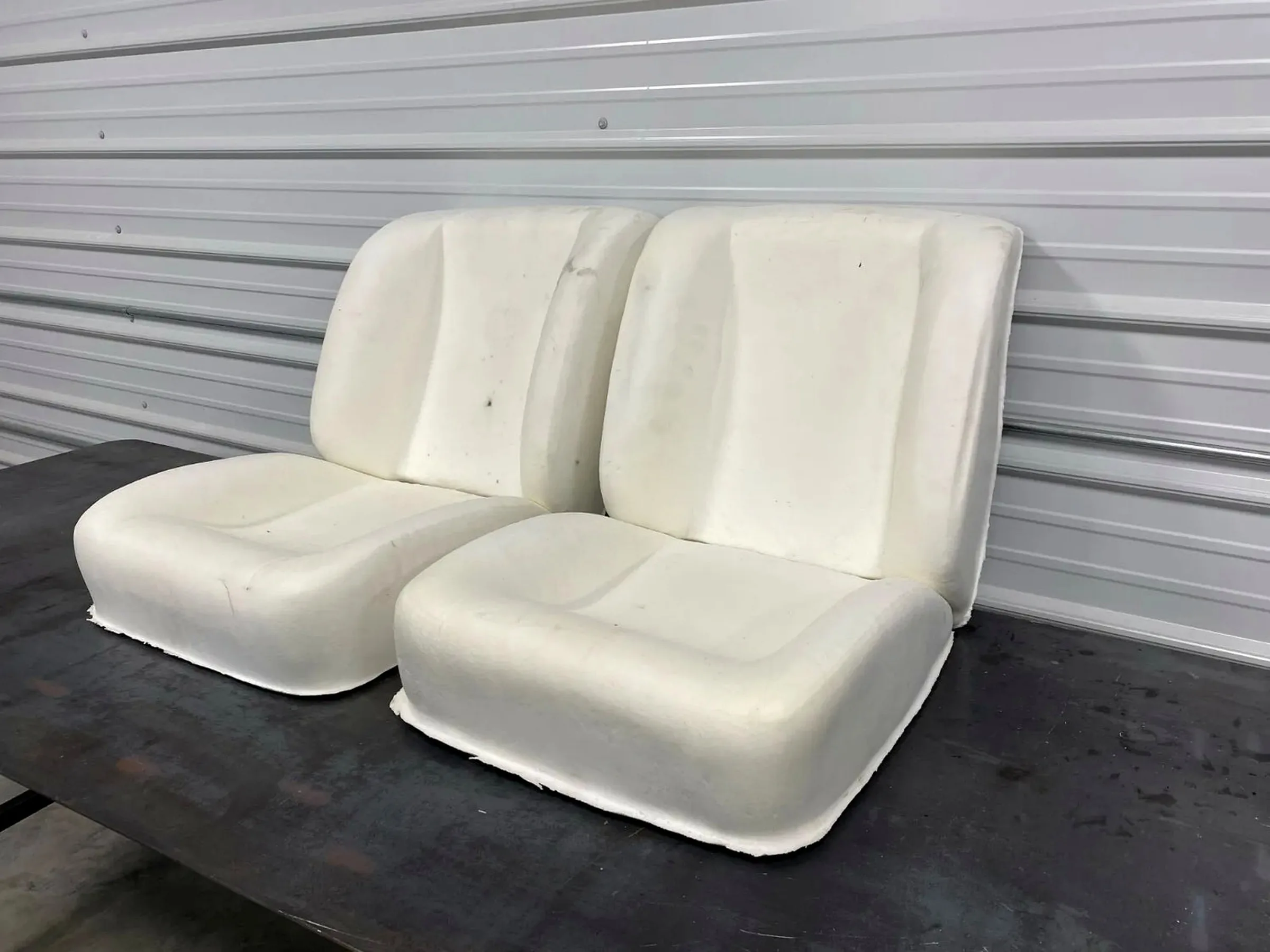 Pair of molded Corvette seat components displayed in the workshop.